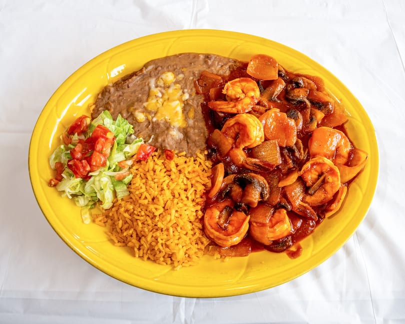 Shrimp with mushrooms and vegetables in red sauce, served with rice, refried beans, and salad.