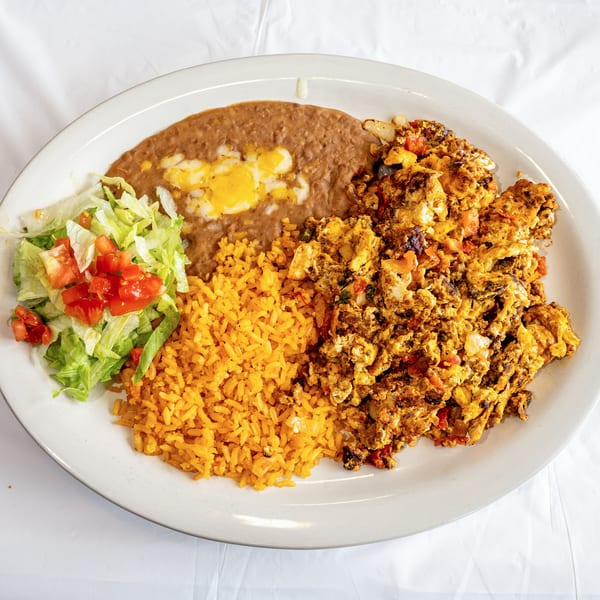 Mexican breakfast plate with scrambled eggs, refried beans, rice, and a side salad.